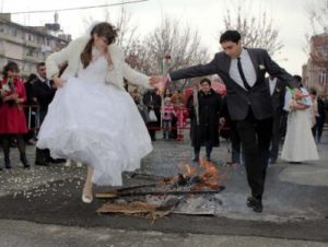 Newlyweds jumping over bonfire